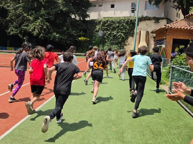 Niños de Tribu corriendo juntos en la cancha, vistos de espaldas