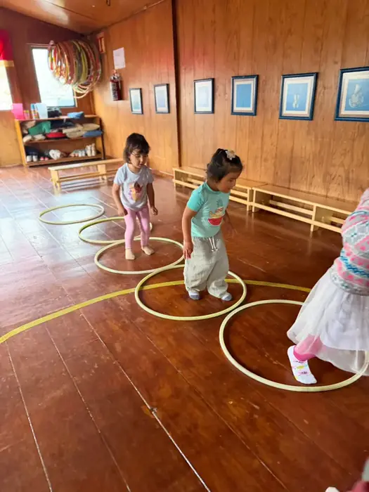 Niñas de After School jugando entre aros sobre el piso de madera del salón