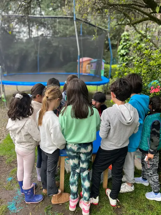 Grupo de niños de Camps de espaldas, reunidos frente al trampolín del jardín