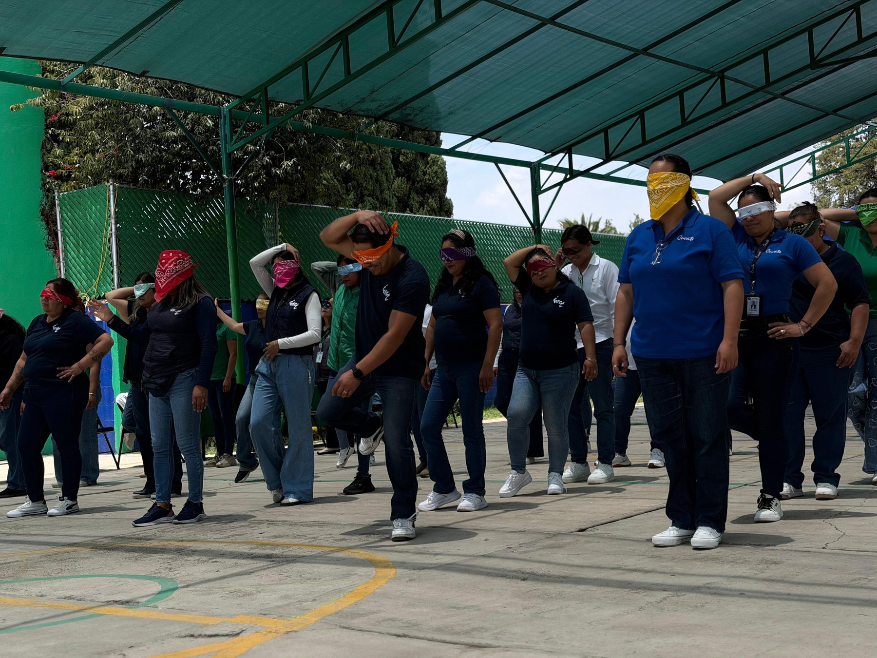 Grupo de adultos de una empresa caminando con los ojos vendados en una cancha, en una dinámica de Team Building de Tribu